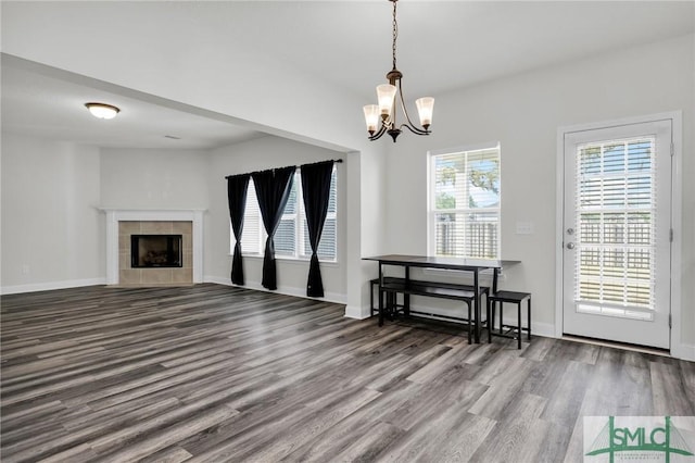 living room featuring baseboards, a tile fireplace, wood finished floors, and an inviting chandelier