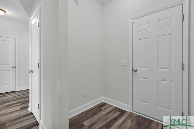 hallway with baseboards and dark wood-style flooring