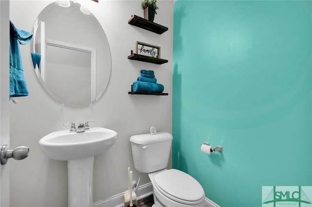 half bath featuring baseboards, a sink, and toilet