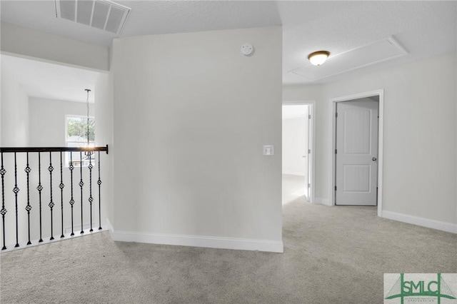 interior space with a chandelier, carpet, visible vents, baseboards, and attic access