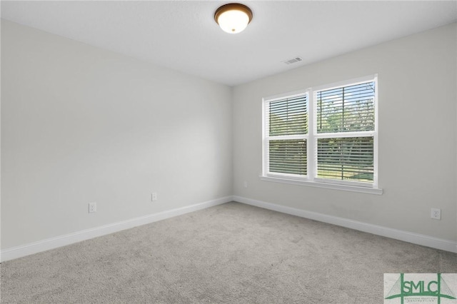empty room with carpet, visible vents, and baseboards