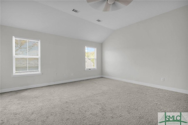 carpeted spare room with lofted ceiling, visible vents, a ceiling fan, and baseboards