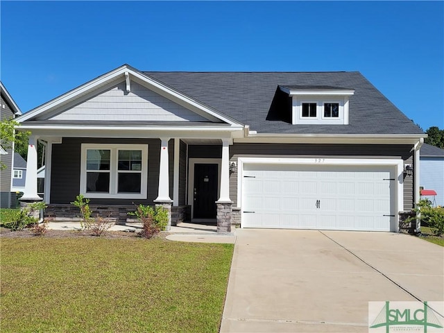 craftsman-style house featuring concrete driveway, covered porch, stone siding, a front yard, and a garage