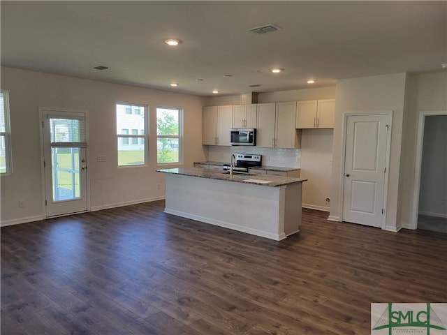 kitchen with visible vents, light stone counters, appliances with stainless steel finishes, and dark wood finished floors