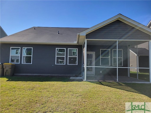 rear view of house with a lawn, a sunroom, and roof with shingles