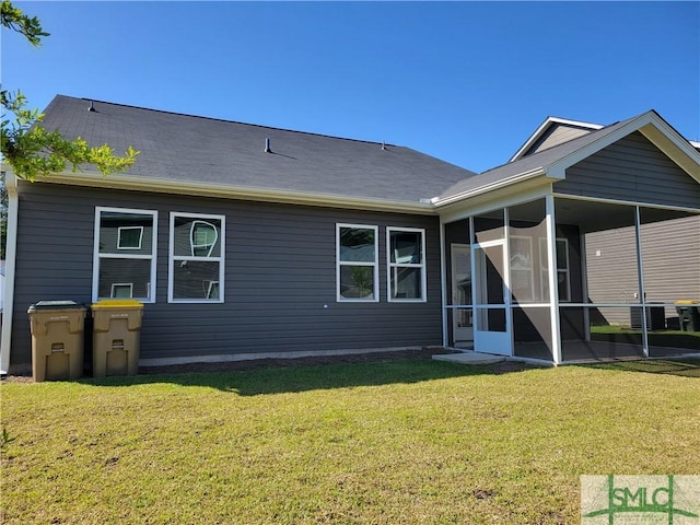 rear view of property featuring a lawn, a sunroom, roof with shingles, and cooling unit