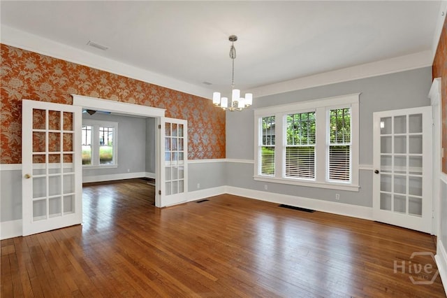 128 E 48th St, Savannah, GA 31405 - unfurnished dining area with wallpapered walls, healthy amount of natural light, wood-type flooring, a chandelier, and french doors