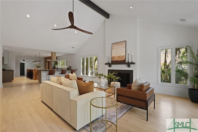 living area featuring ceiling fan, beamed ceiling, high vaulted ceiling, and light wood-style floors