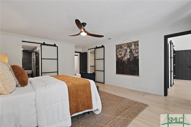 bedroom featuring ornamental molding, visible vents, a barn door, and wood finished floors