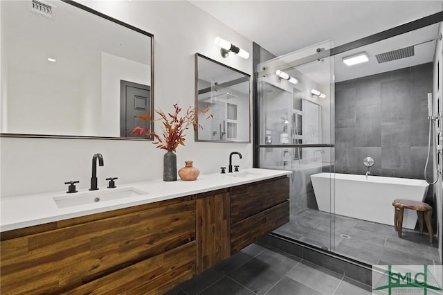 full bathroom featuring a freestanding bath, tile patterned flooring, visible vents, and a sink
