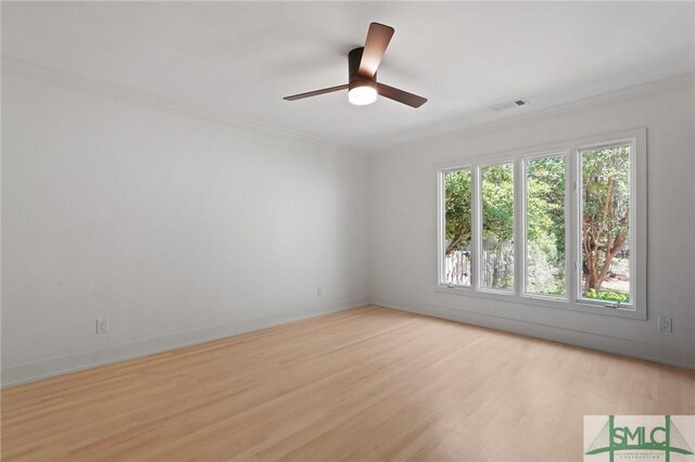 empty room featuring a ceiling fan, ornamental molding, light wood-type flooring, and visible vents