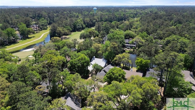 drone / aerial view featuring view of golf course, a wooded view, and a water view