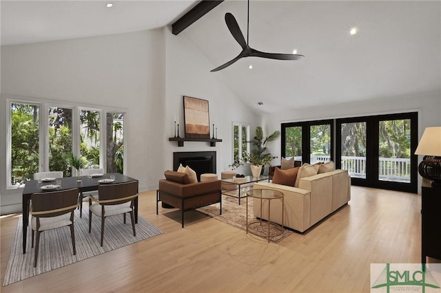 living area with light wood finished floors, ceiling fan, high vaulted ceiling, a fireplace, and beam ceiling