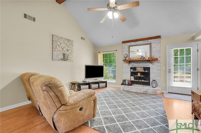 living area with baseboards, a brick fireplace, visible vents, and plenty of natural light