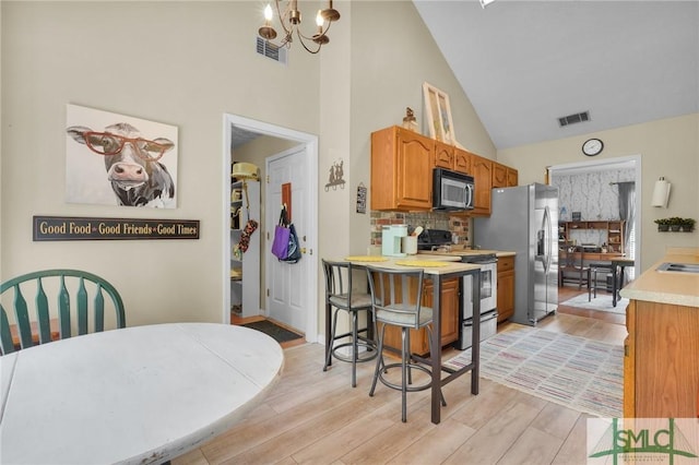 kitchen with visible vents, a notable chandelier, light countertops, high vaulted ceiling, and appliances with stainless steel finishes