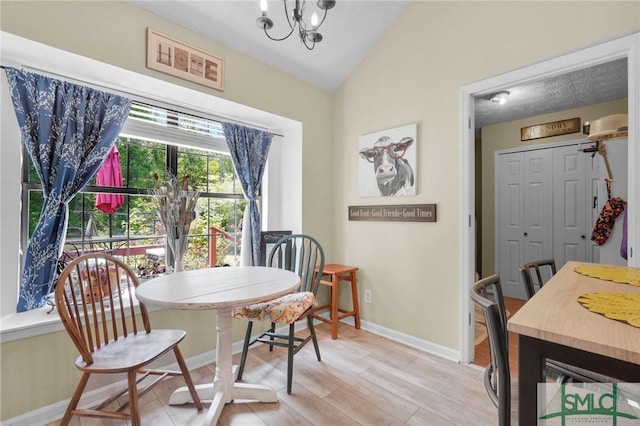 dining space with baseboards, lofted ceiling, light wood-style flooring, and a notable chandelier