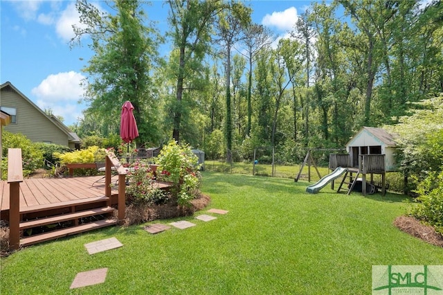 view of yard with a wooden deck, a playground, and fence