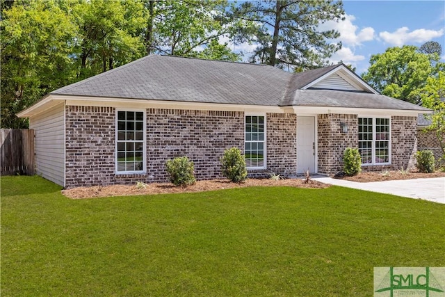 ranch-style home with brick siding, a shingled roof, a front lawn, and fence