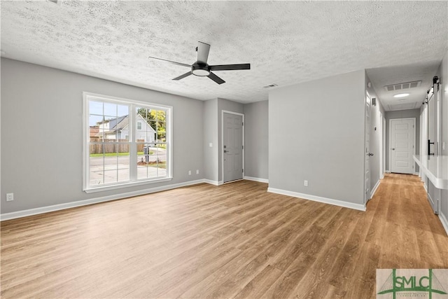 unfurnished living room with a textured ceiling, baseboards, visible vents, light wood-style floors, and ceiling fan