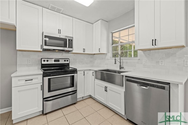 kitchen featuring a sink, light tile patterned floors, light countertops, appliances with stainless steel finishes, and visible vents