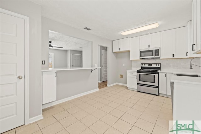 kitchen featuring light countertops, backsplash, visible vents, a sink, and appliances with stainless steel finishes