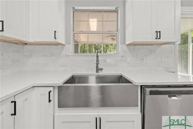 kitchen with tasteful backsplash, stainless steel dishwasher, white cabinetry, and a sink