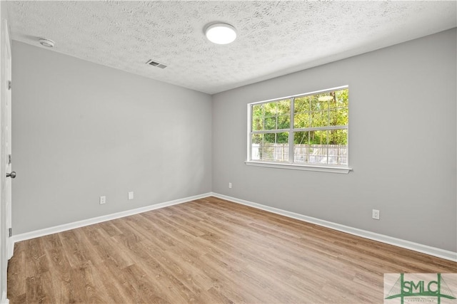 empty room featuring wood finished floors, a textured ceiling, and baseboards