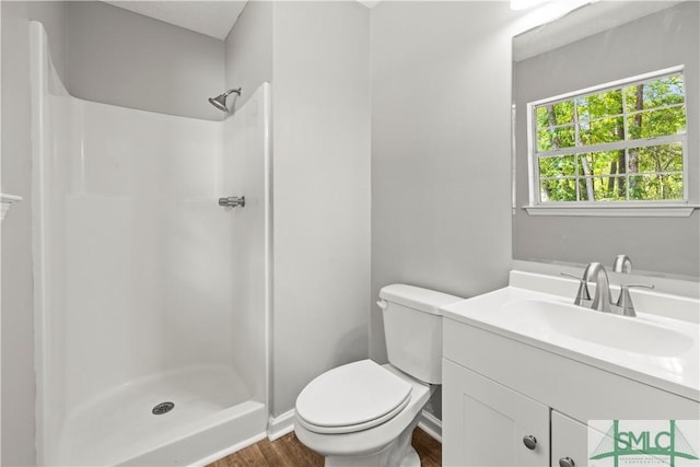 bathroom featuring toilet, vanity, wood finished floors, and a stall shower
