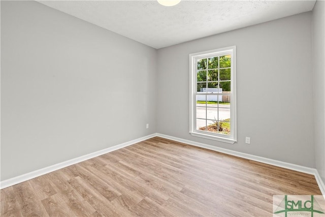 unfurnished room with baseboards, wood finished floors, and a textured ceiling
