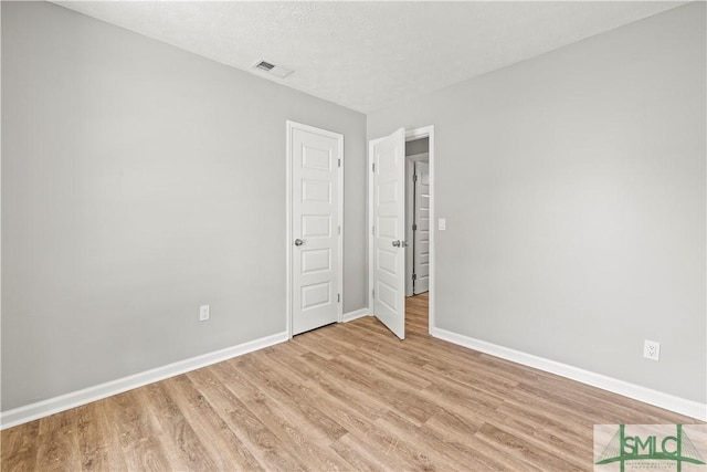empty room featuring visible vents, light wood finished floors, and baseboards