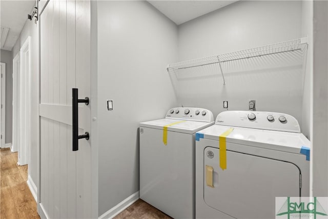 laundry room featuring light wood finished floors, baseboards, washer and dryer, and laundry area