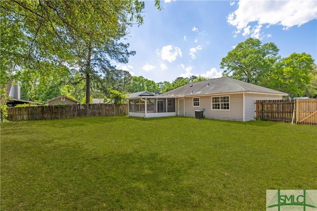 rear view of property with a fenced backyard, a sunroom, and a yard