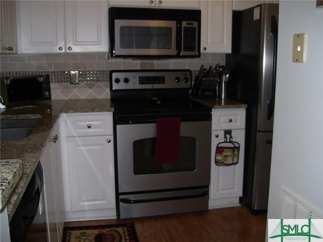 kitchen with white cabinets, dark wood-style floors, stainless steel appliances, light stone countertops, and tasteful backsplash