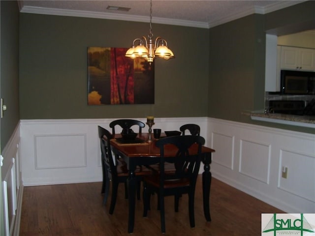 dining area with a decorative wall, wood finished floors, and visible vents