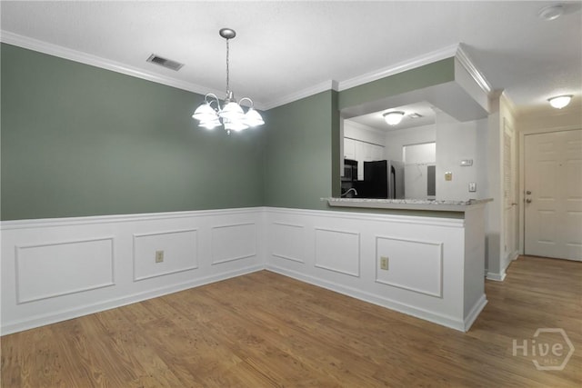 12300 Apache Ave Unit 1212, Savannah, GA 31419 - unfurnished dining area featuring ornamental molding, a wainscoted wall, wood finished floors, a chandelier, and a decorative wall