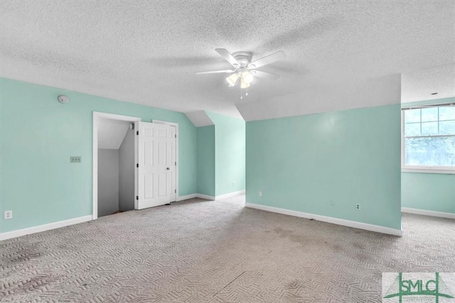 additional living space featuring a textured ceiling, lofted ceiling, carpet floors, and a ceiling fan