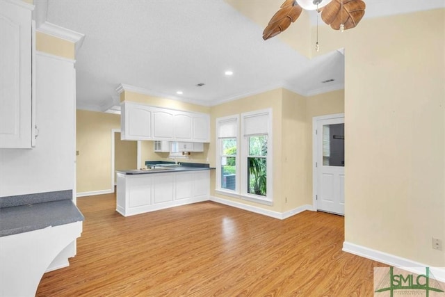 kitchen with white cabinets, light wood-style floors, dark countertops, and crown molding