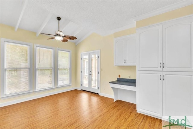 interior space featuring light wood-style floors, a textured ceiling, a ceiling fan, and vaulted ceiling with beams
