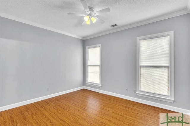 unfurnished room featuring a textured ceiling, wood finished floors, visible vents, and crown molding
