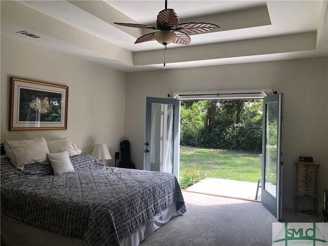 bedroom featuring visible vents, access to exterior, ceiling fan, a tray ceiling, and carpet