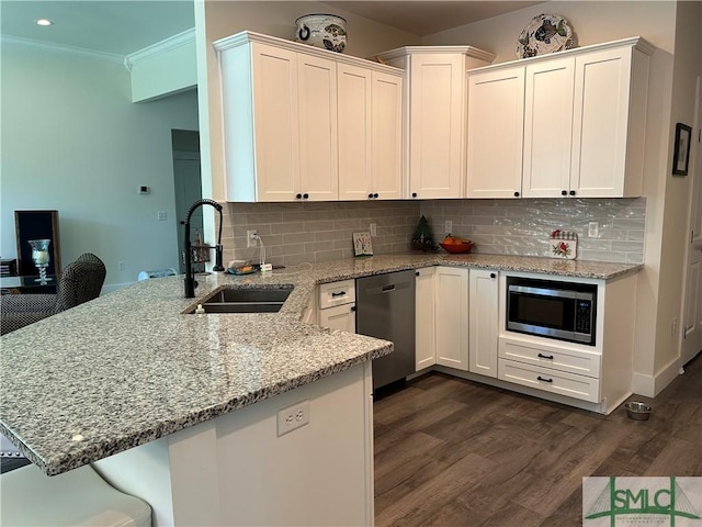 kitchen with a sink, stainless steel appliances, a peninsula, tasteful backsplash, and dark wood-style floors