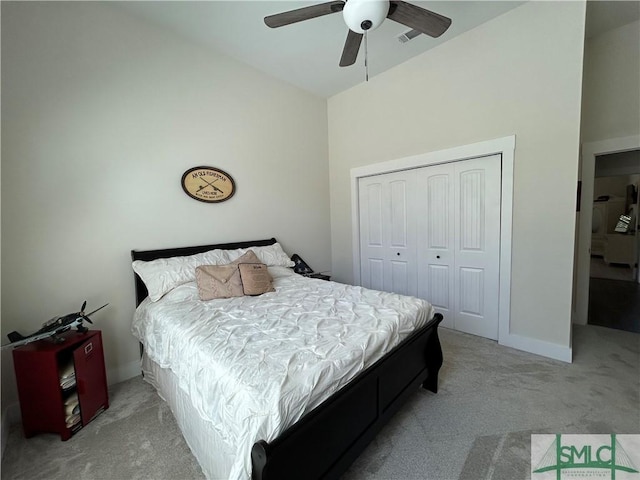 bedroom featuring a closet, ceiling fan, light carpet, and vaulted ceiling