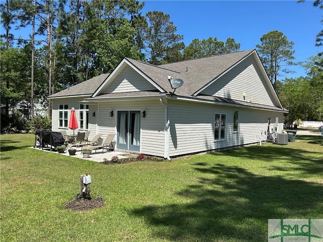 back of property with a yard, a patio, central AC unit, and roof with shingles