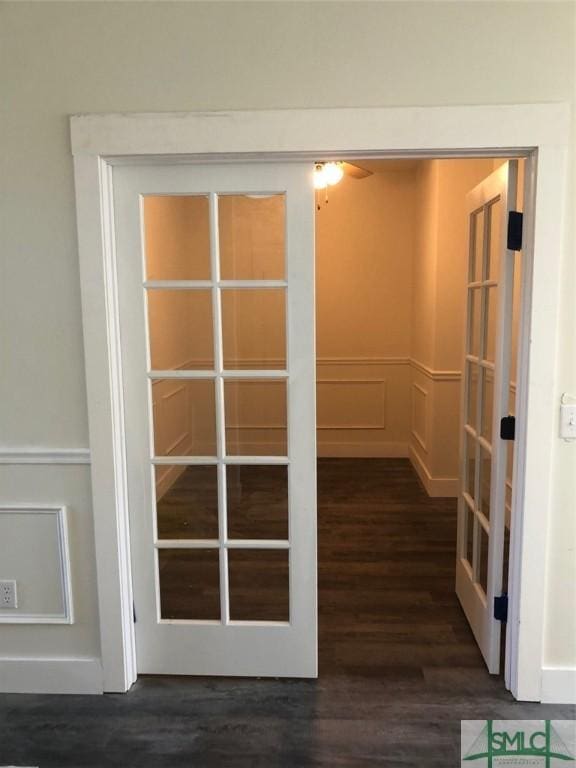 interior space with a wainscoted wall, french doors, wood finished floors, and a decorative wall