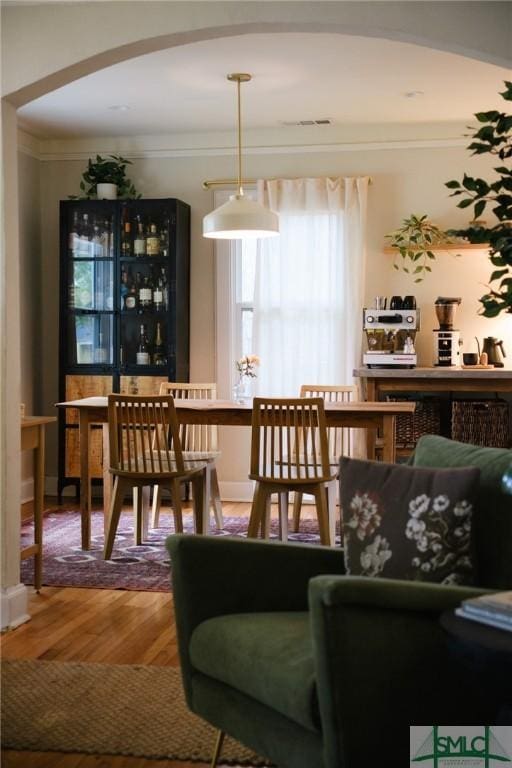interior space with arched walkways, wood finished floors, and ornamental molding