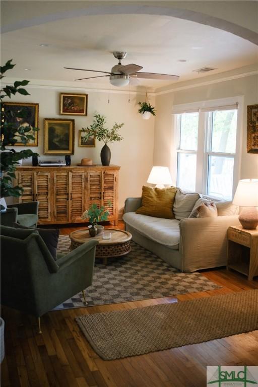 living room with arched walkways, visible vents, hardwood / wood-style flooring, and ceiling fan