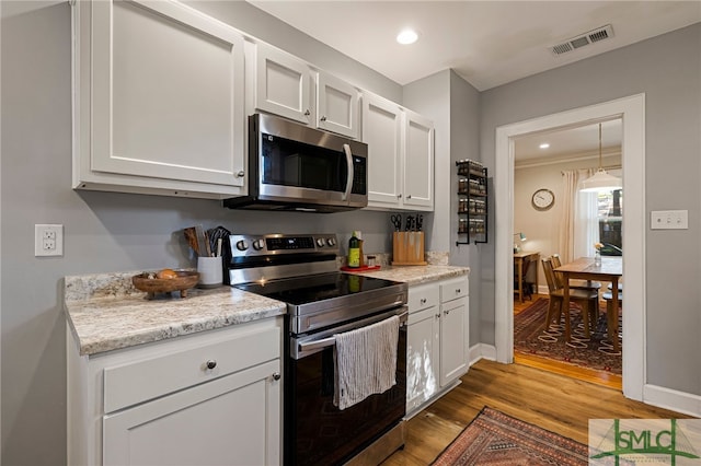 kitchen featuring white cabinetry, appliances with stainless steel finishes, wood finished floors, and visible vents