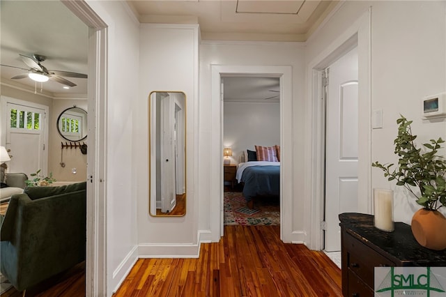 corridor featuring baseboards, wood finished floors, and ornamental molding