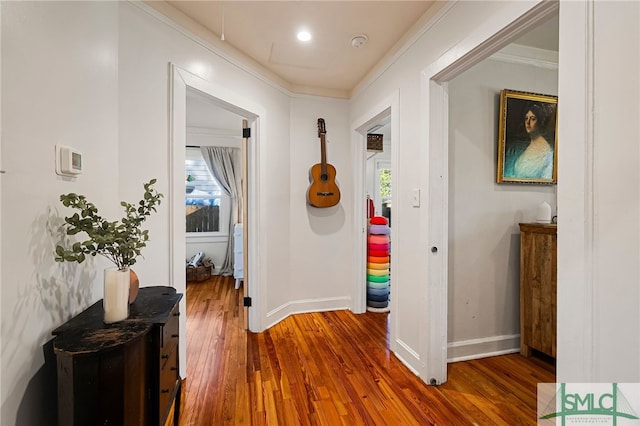 hallway featuring hardwood / wood-style flooring, baseboards, ornamental molding, and plenty of natural light