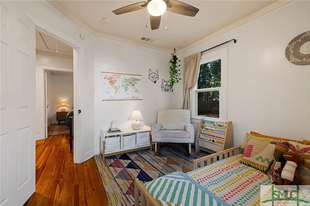 bedroom featuring attic access, visible vents, wood finished floors, ceiling fan, and ornamental molding